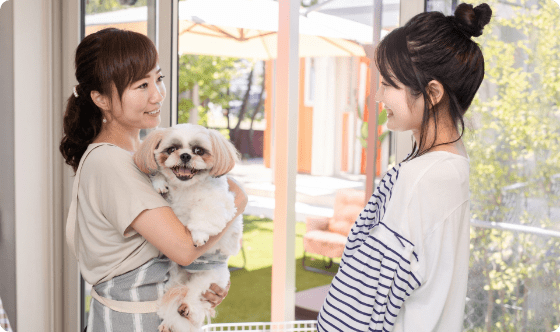 ペットシッターがお客様の犬を抱えてお客様が楽しそうに話す様子