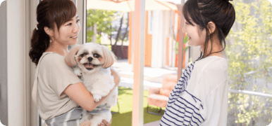 ペットシッターがお客様の犬を抱えてお客様が楽しそうに話す様子